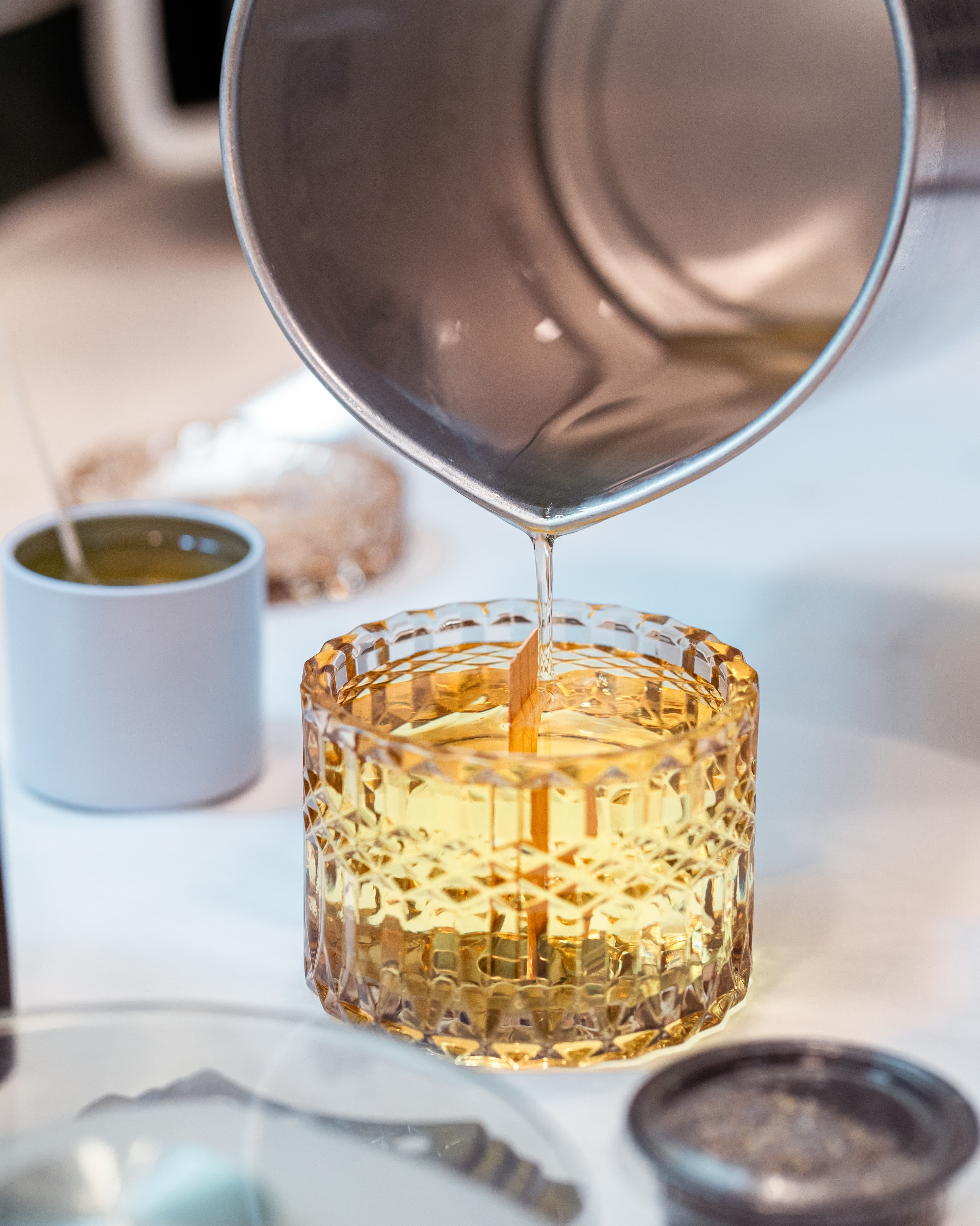Candle wax being poured into a glass jar